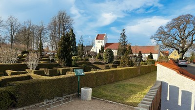 En smuk have med høje hegn og en lille springvand i forgrunden
