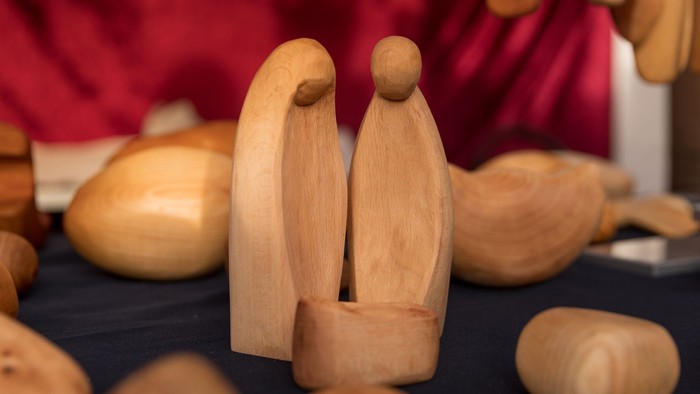 Holzfiguren, darunter zwei menschliche Figuren und Tiere, auf schwarzer Oberfläche