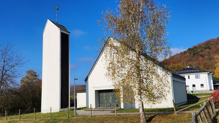 Weißes Gebäude mit Turm neben Baum und Berg