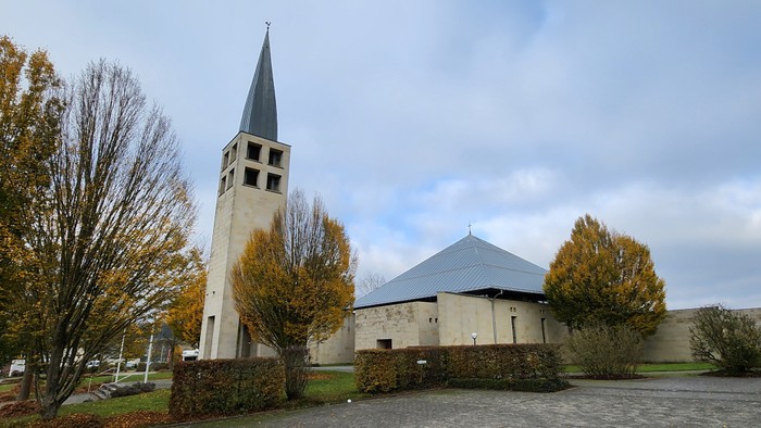 Kirchengelände mit hohem Turm und Herbstbäumen