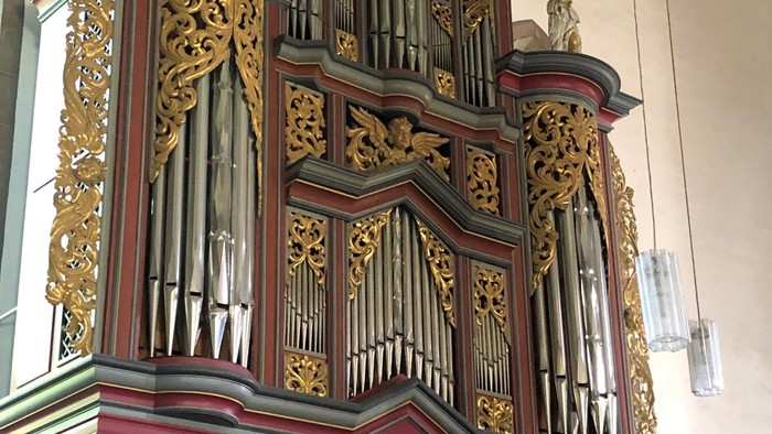 Große, aufwendig gestaltete Pfeifenorgel mit goldenen Akzenten und rotem Sockel.