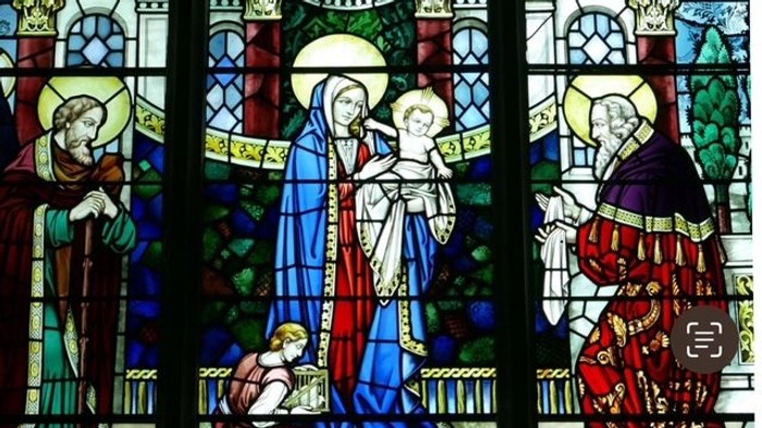 Buntglasfenster mit religiösen Figuren in farbenfroher Kleidung.