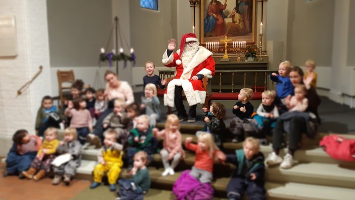 Børn og voksne samlet om Santa Claus i kirke.