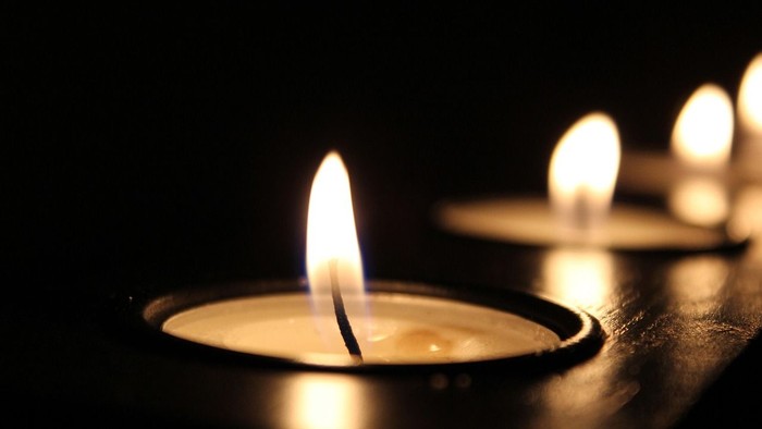 Sanft leuchtende Kerzen in warmem Licht vor dunklem Hintergrund, die eine ruhige und intime Atmosphäre schaffen.