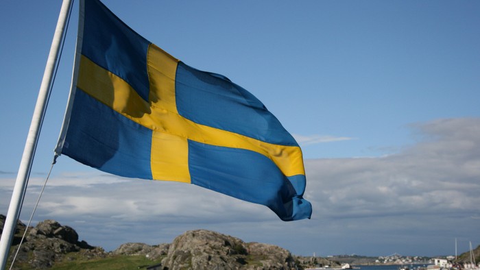En blå og gule flag på en mast ved en havn.
