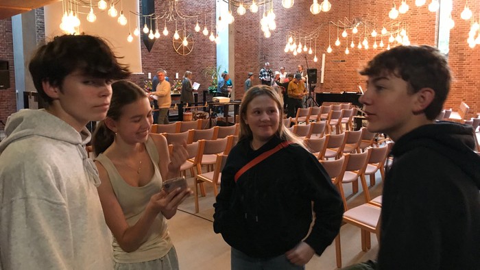 Fire unge står i en restaurant og ser på en telefon.