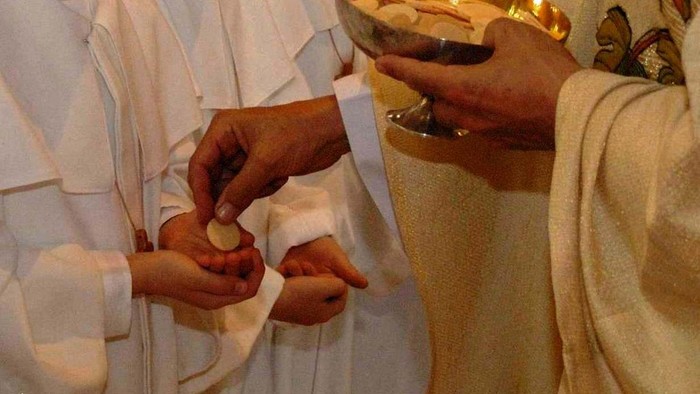 Personen in weißen Gewändern halten eine Schale mit Gegenständen