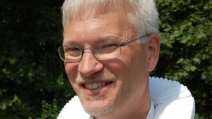 Mand med hvid krage og briller.