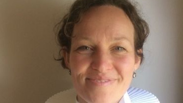 En kvinde med hvid krage og sort blouse.