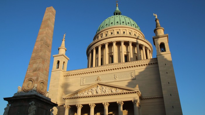 Das Bild zeigt eine große Kuppelkirche mit grünem Dom und hoher Säule.