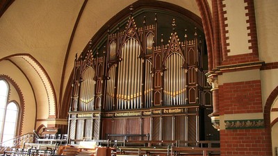 Elegante Pfeifenorgel in einem prächtigen, gewölbten Kircheninnenraum mit Holz- und Ziegelverzierungen.