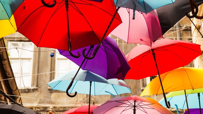 Farverige paraplyer hænger opad i en by.