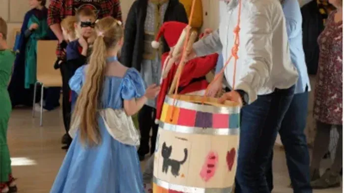Børn i festlige kostumer danser og leker på indendørs arrangement