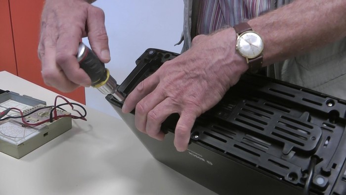 Person repariert ein elektronisches Gerät.