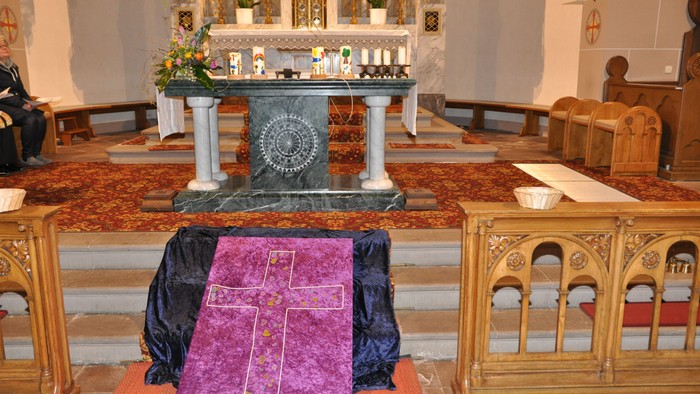 In der Kirche ist ein Altar mit Kerzen und Blumen geschmückt.