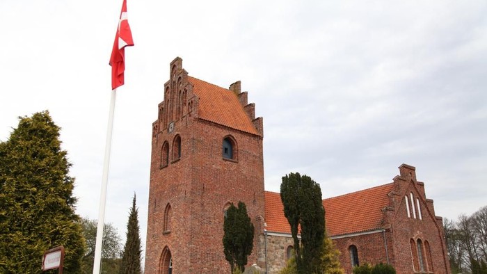 En rød kirke med tårn og en flagstang med rødt flag.