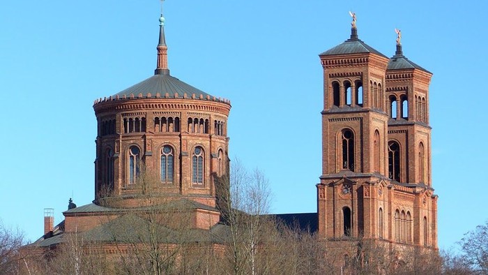 Zwei Türme einer Kirche vor bewölktem Himmel