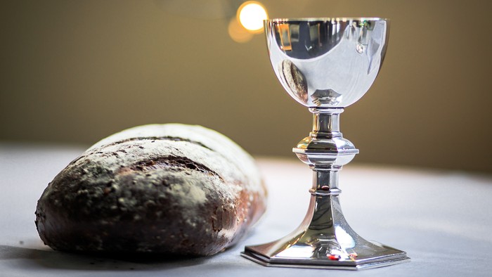 En sølv kalk og et brød på en hvid tabledeklædning