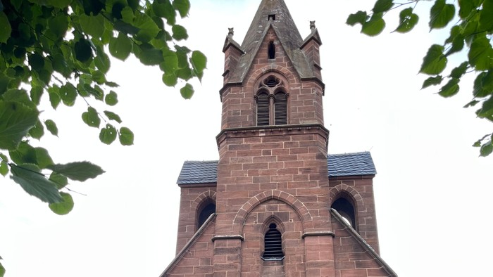 Kirche mit hohem Turm und gelber Tür.