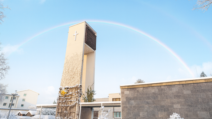 Verschneite Kirche Neu-Buckow bei Sonnenschein und Regenbogen im Hintergrund