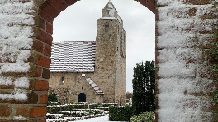 En snedækket muråbning med kirke i baggrunden