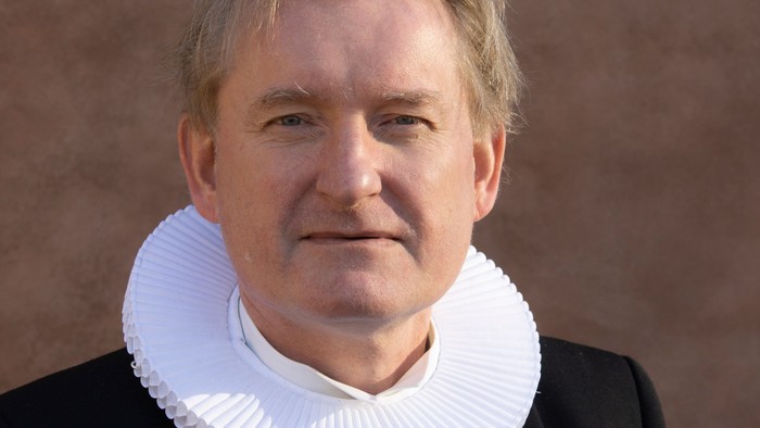 En mand med hvid krage og sort kappe.