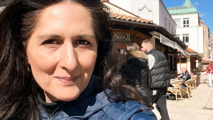 Kvinde, der tager selfie med barn i blå jakke udendørs.