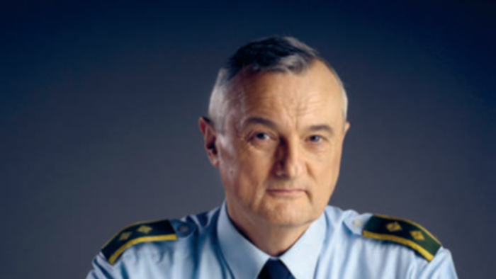 En mand i uniform sidder ved et bord.