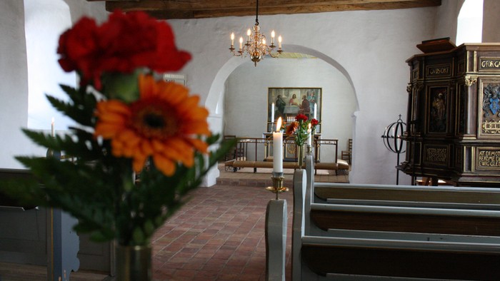 En kirkeindendørs med blomster og bænke