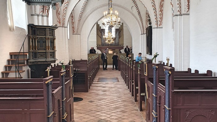 Kirkeinteriør med trækirkebænke og krystalkrone