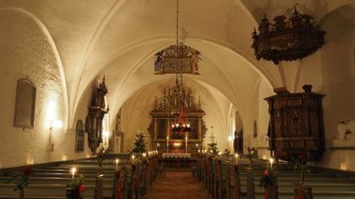 Kirkeinteriør med kirkebænke, alter og lysekroner