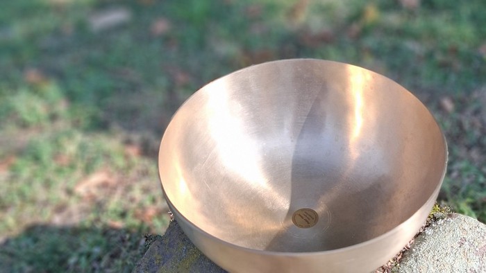 Ein Kupferbecken steht auf einem Stein im Freien.