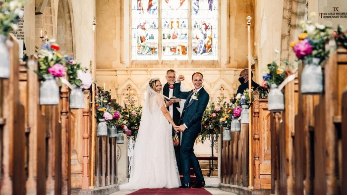 Wedding ceremony in church with bride, groom, and officiant.