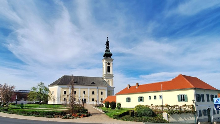 Weißes Gebäude mit hohem Turm und rotem Dach unter blauem Himmel