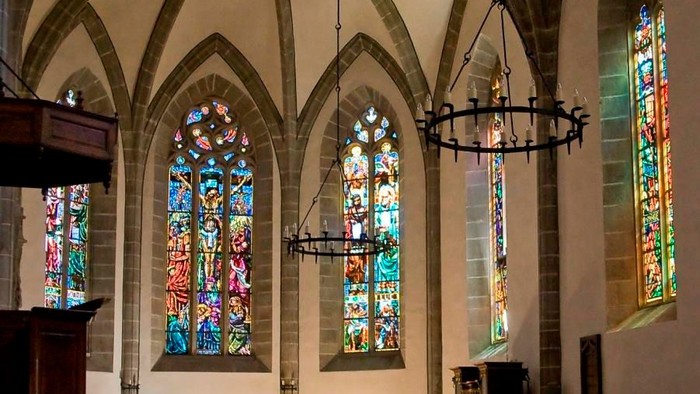 Indre del af kirke med farverige vinduer og hængende lygter