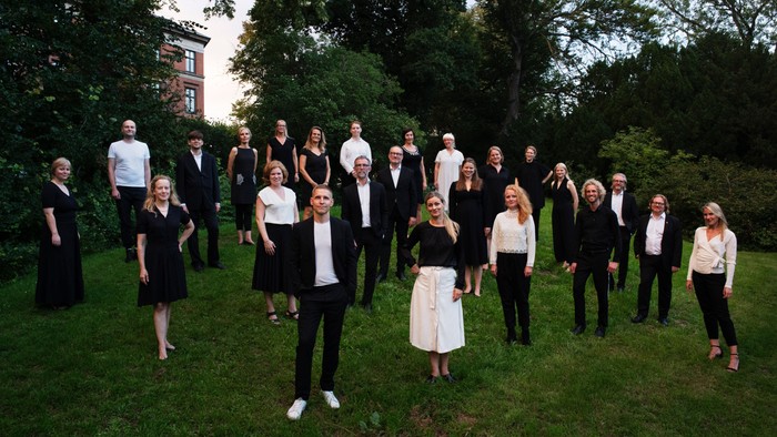 En formel gruppe af mænd og kvinder i sort og hvidt tøj, der poser udendørs i en have.