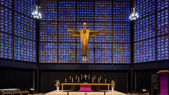 Die Kirche mit einem großen goldenen Kruzifix und bunten Glasfenstern.