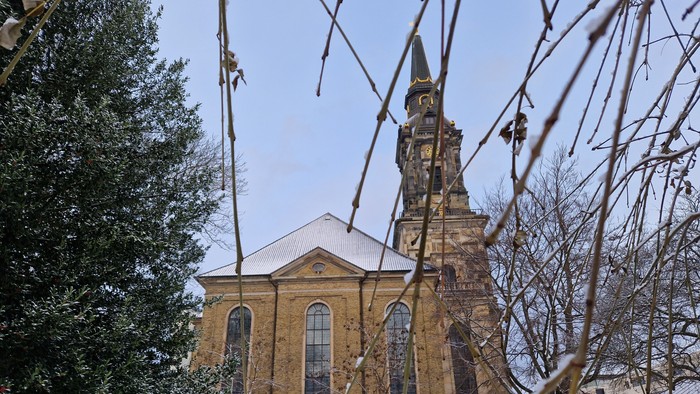 En kirke med tårn og klokke, omgivet af sne og træer