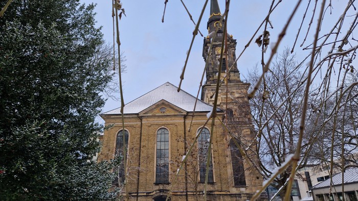 En kirke med tårn og klokke, omgivet af sne og træer