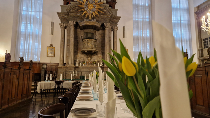 Elegant kirkeinteriør med opstillede borde, gule tulipaner og prægtigt pibeorgel i baggrunden.
