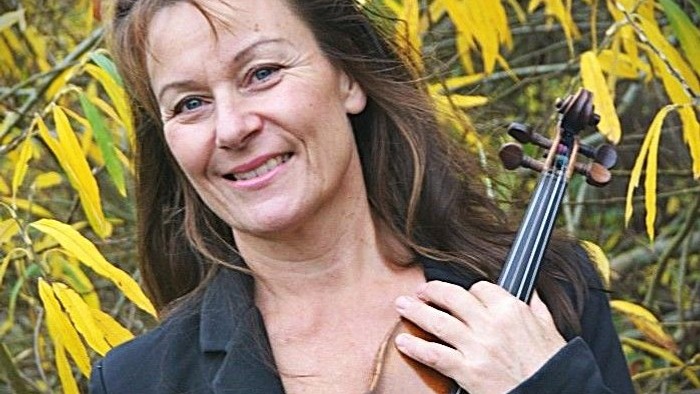Kvinde spiller violin i træerne