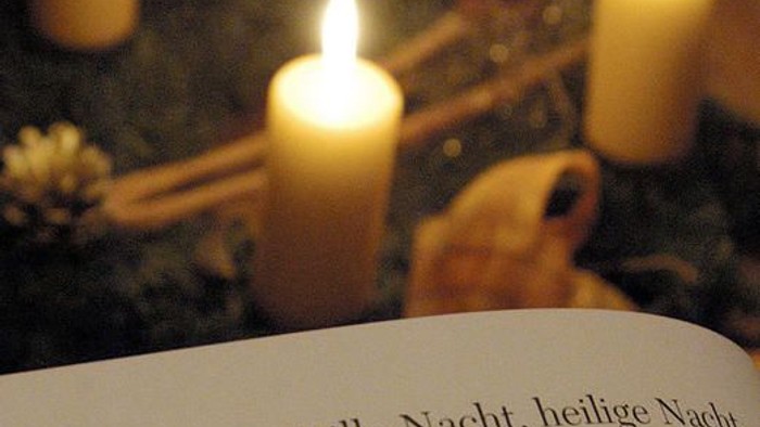 Notenblatt mit brennenden Kerzen darauf.