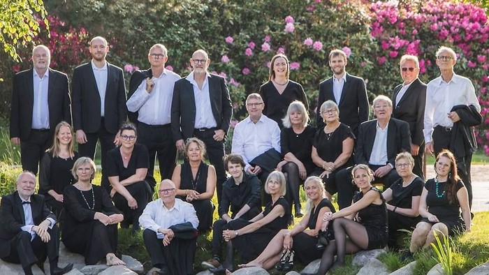 Gruppe af mennesker, der poser nær dam med blomster i baggrunden