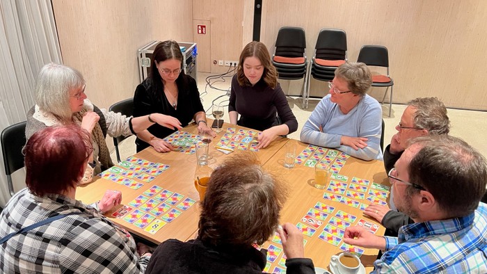 Eine Gruppe von Menschen spielt Scrabble an einem Tisch.