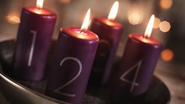 Fire røde adventstænder med tal på 1, 2, 3 og 4 i en sølvskål.