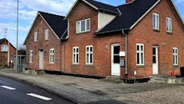 En række nybyggede røde teglboliger med hvide vinduer og sorte tag.