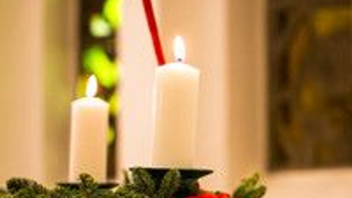 Stearinlys på krans med rød sløjfe