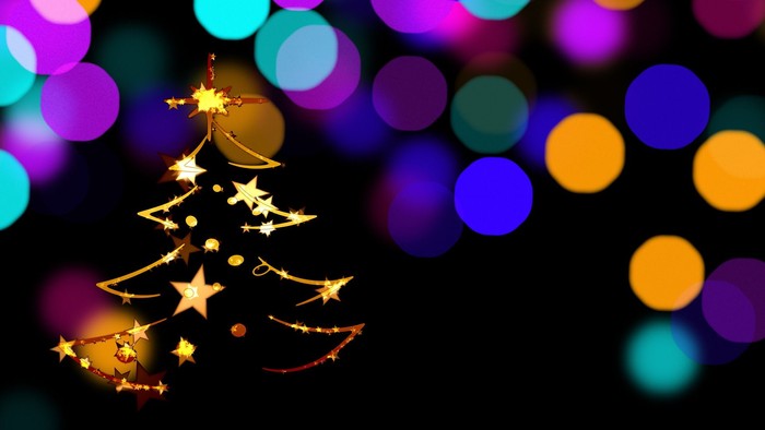 Et gyldent juletre med stjerner foran farverige lysblomster.