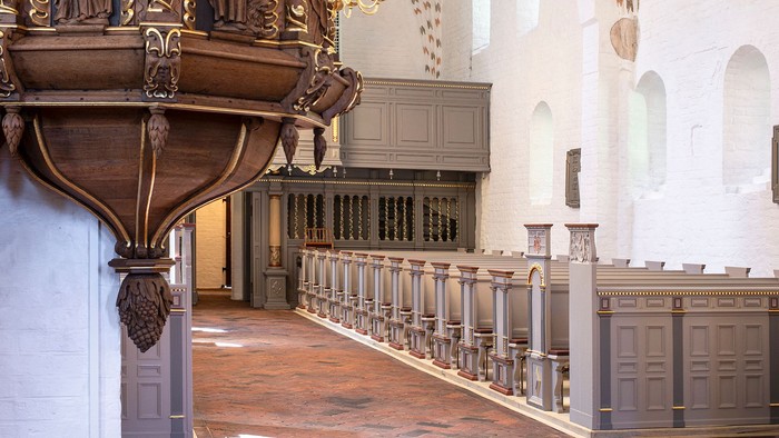 Indre del af kirke med altertavle og bænke.