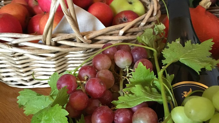 En korbund med æbler og en håndfuld druer på bordet